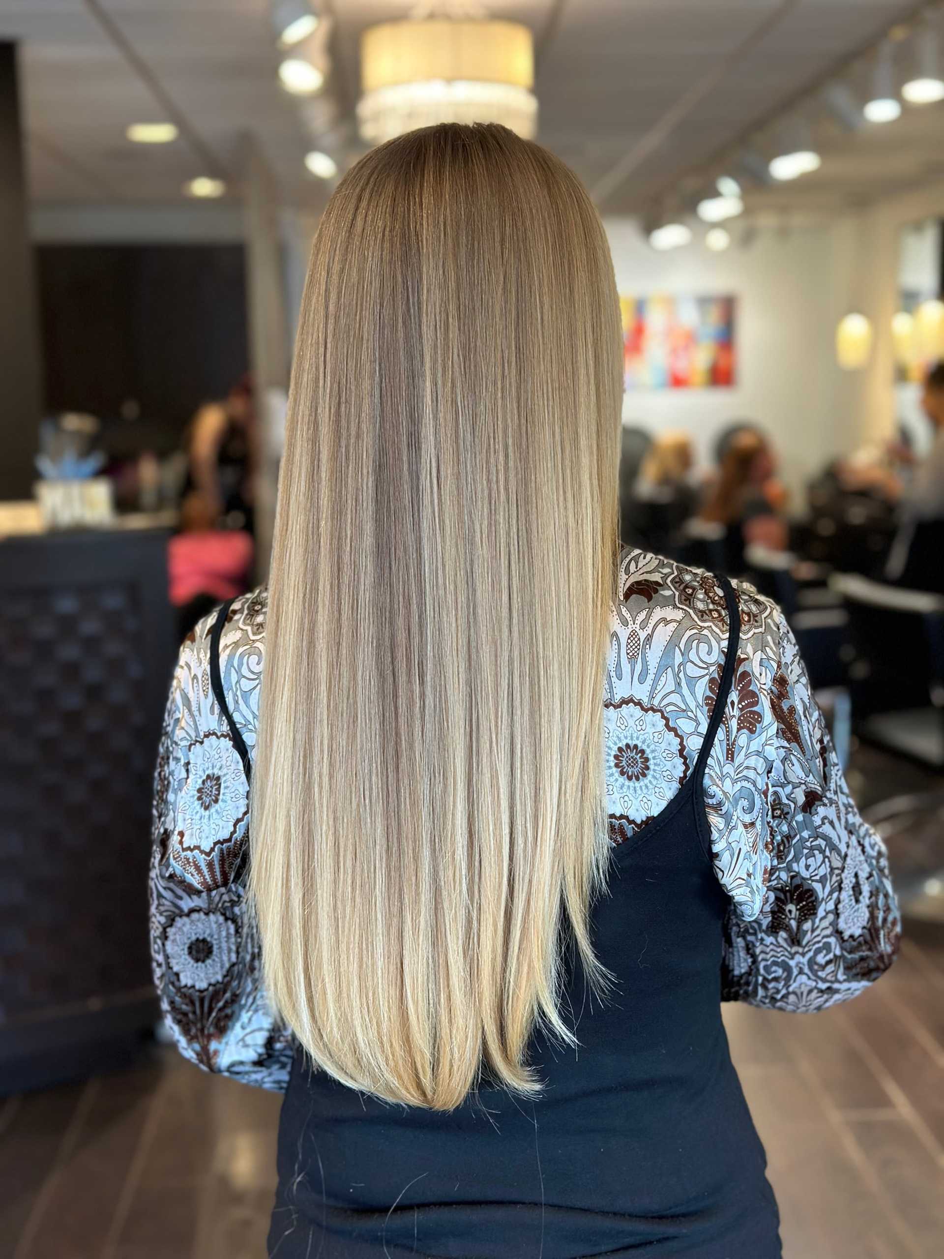 Woman with long, straight blonde hair in a salon setting.
